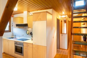 A kitchen with wooden cabinets, a stainless steel oven, and a window. - Apartment 'Obertalblick' on a Farm Holiday (Eisenbach)