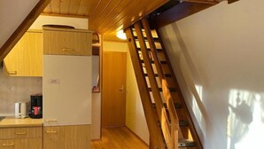 Ein Holzinnenraum mit einer Küche, einer Treppe und einer Tür zu einem weiteren Raum.