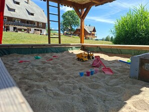 A sandy play area with toys and a wooden structure. - Apartment 'Obertalblick' on a Farm Holiday (Eisenbach)