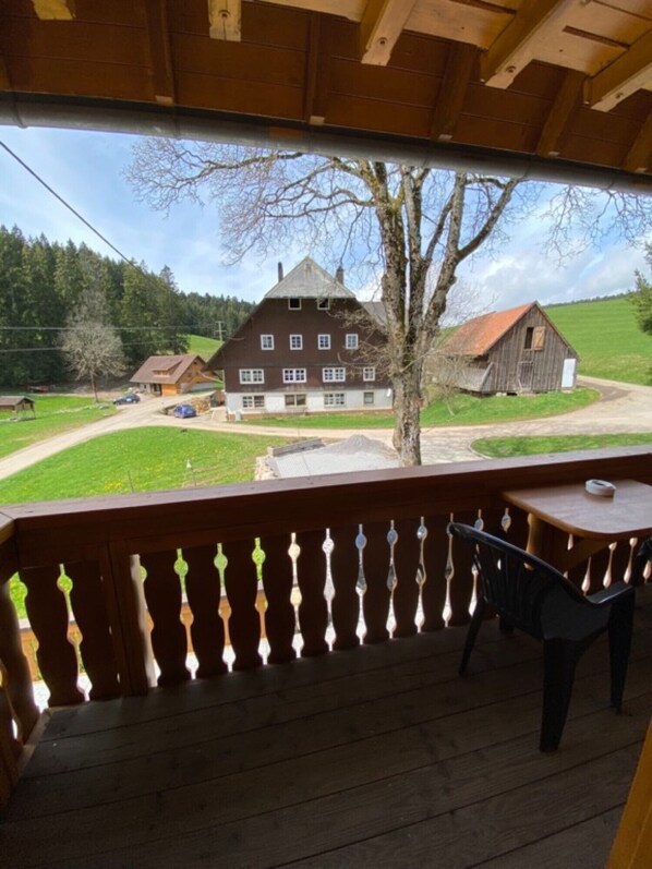 Une terrasse en bois offrant une vue sur une grande maison et une grange.