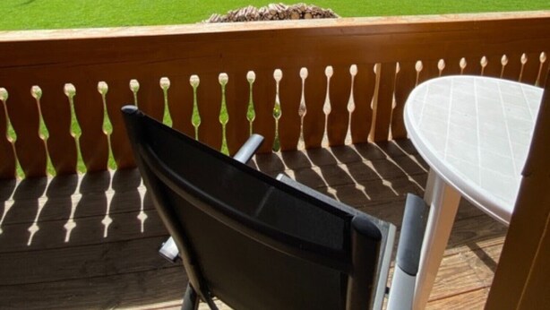 A wooden deck with a table and chairs, overlooking a green field and forested hills. - Holiday Apartment 'Untertalblick' with Shared Garden and Balcony, Farm Stay (Eisenbach)