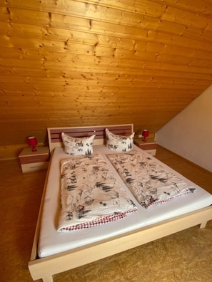 A wooden-paneled room with a bed, two bedside tables, and a red lamp on each table.