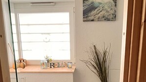 Eine Küche mit Fenster, einem Bild, einem Holzschrank, einer Pflanze und einer Laterne.