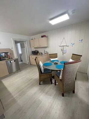 Ett modernt kök med en matplats, med en central köksö, inbyggda skåp och en hängande lampa.