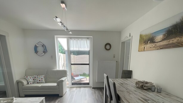 Ein modernes Wohnzimmer mit einer Couch, einem Couchtisch und einem Essbereich mit Tisch und Stühlen.