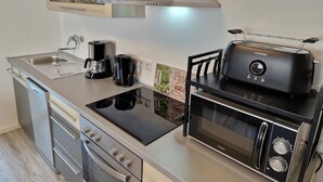 Una cocina compacta con horno integrado, microondas, tostadora y cafetera.