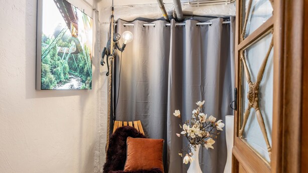 Una stanza con vista su spazi verdi, una poltrona con una coperta in pelliccia, un vaso bianco con fiori e una porta in legno.