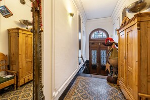 A hallway with wooden cabinets, a bench, a mirror, and a patterned floor.