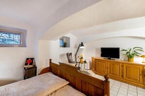 A bedroom with a wooden bed, a television, a cabinet, and a window with a decorative grille.