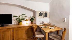 Un tavolo da pranzo in legno con sedie, una televisione su un mobile, piante in vaso e decorazioni a parete.