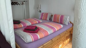 A bedroom with a wooden bed, a wardrobe, and a hanging rack. - Studio Apartment 'Wohnung 1' with Private Terrace and Wi-Fi (Oberhof)