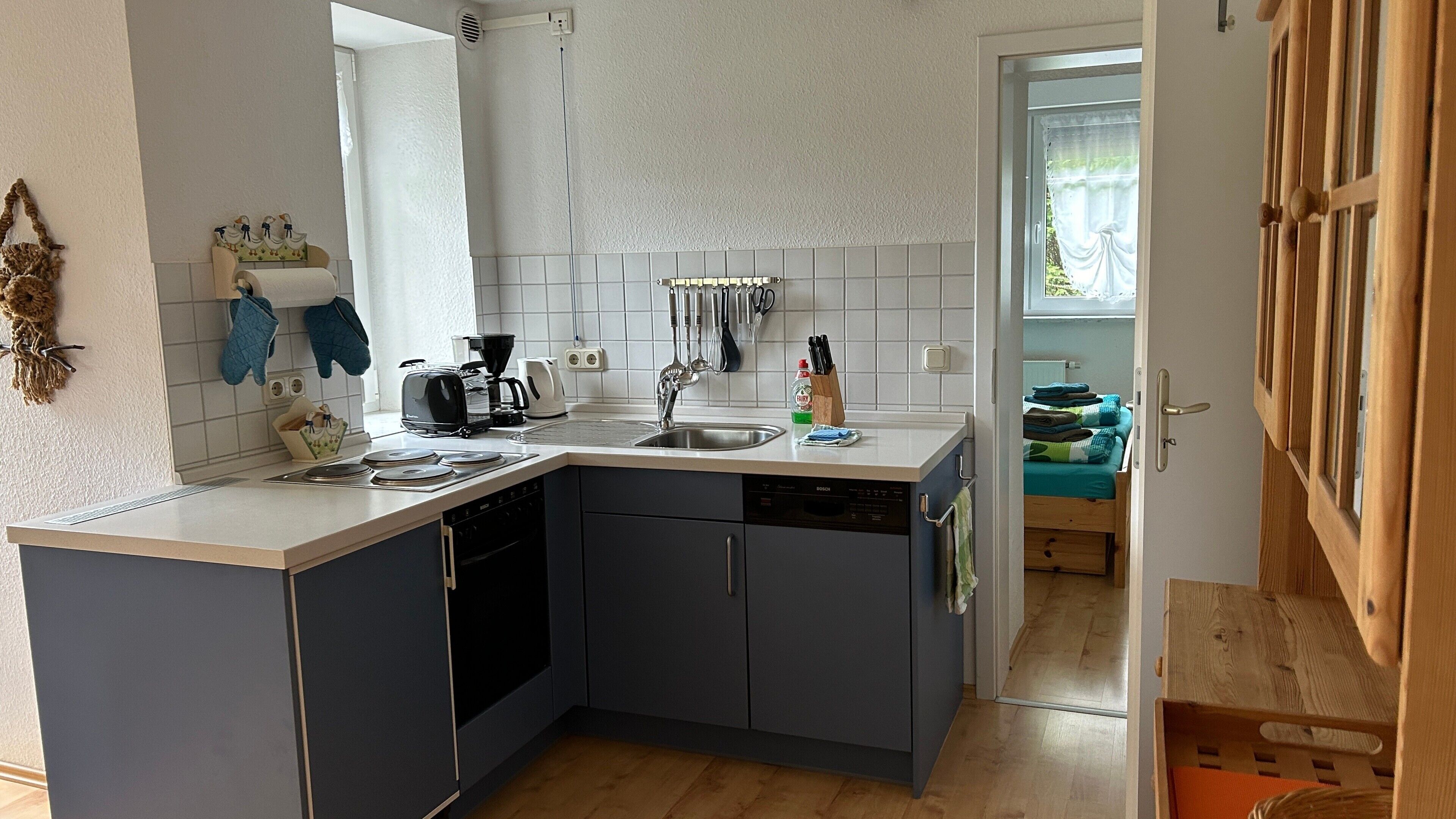 Una cocina compacta con lavavajillas Bosch, cafetera y fregadero.