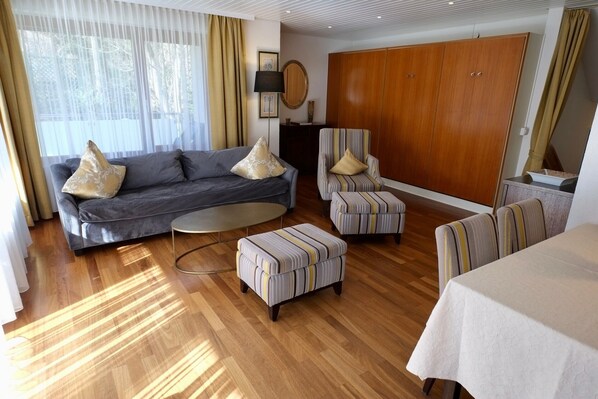 A living room with a sofa, armchairs, ottoman, and a dining table. - Apartment Mattenweg - Appartement 1 - 'Gustav Klimt' (Hinterzarten)