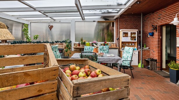 Un invernadero con cajas de madera llenas de manzanas, techo de paja y paredes de ladrillo.