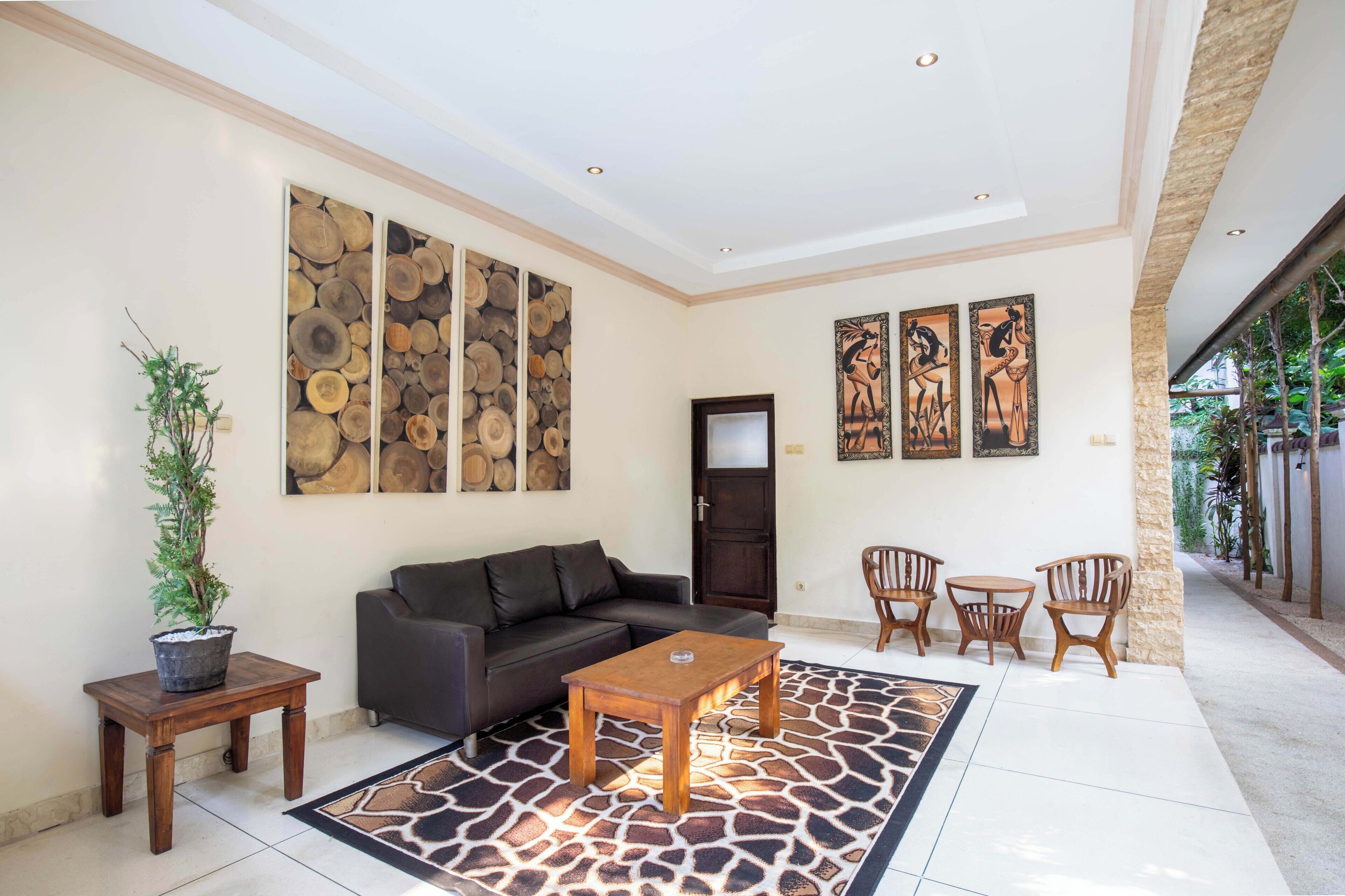 A modern living room with a sofa, coffee table, and chairs, a potted plant, and artwork on the walls.