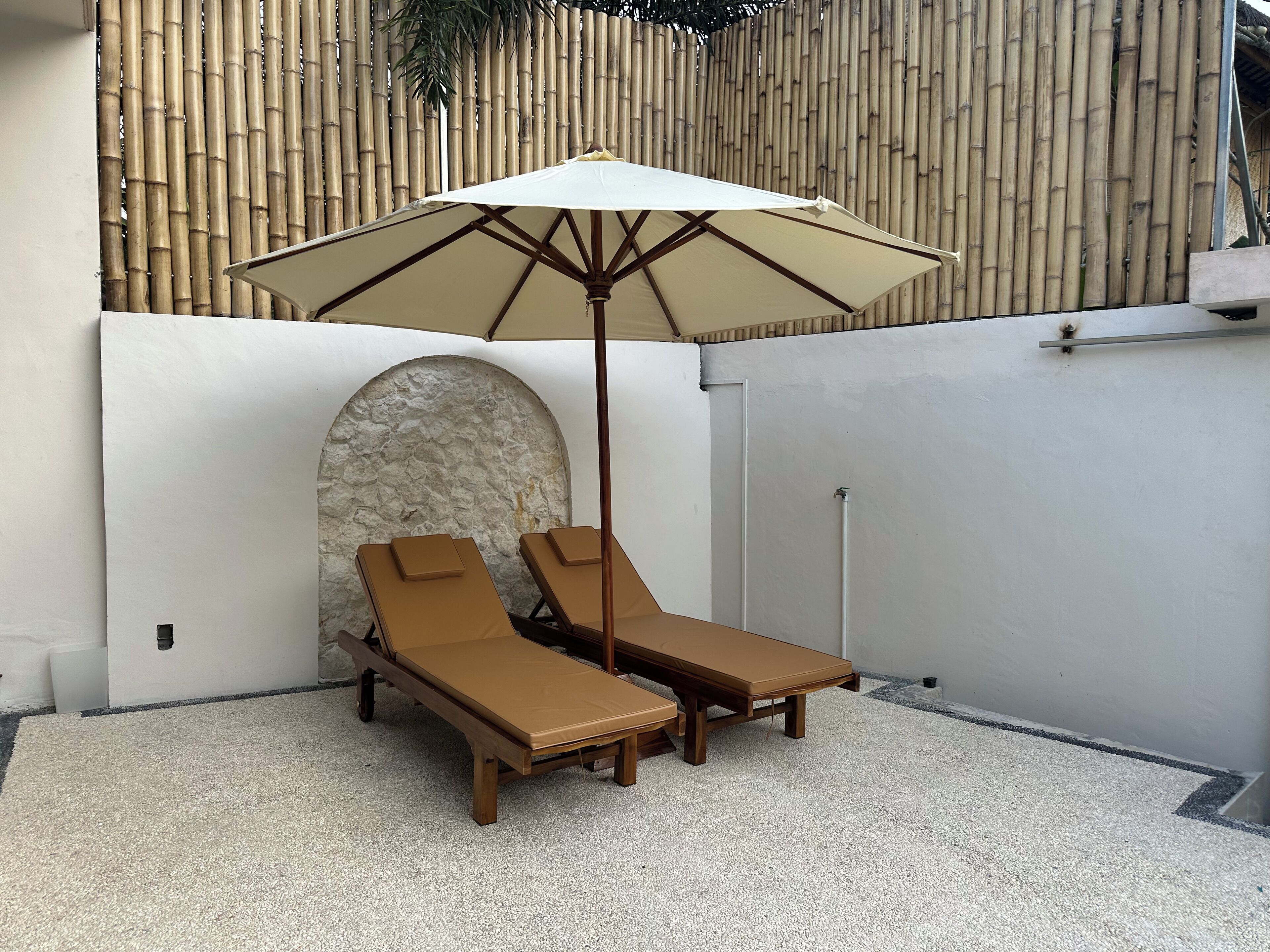 Un petit espace extérieur aménagé avec deux fauteuils et un grand parasol.