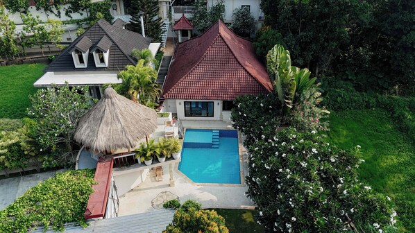 A house with a swimming pool, surrounded by lush greenery and a thatched-roof structure. - Ombe Villa (Aikmel)