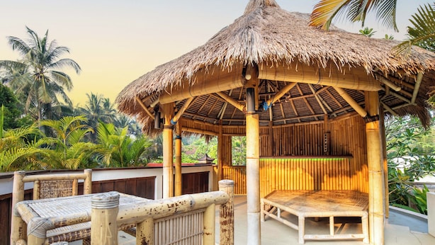 A bamboo structure with a thatched roof, surrounded by lush greenery. - Ombe Villa (Aikmel)