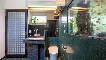 A modern bathroom with a marble sink, a toilet, and a glass enclosure with fish.