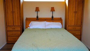 A bedroom with a bed, two bedside lamps, and wooden wardrobes. - Quiet Mountain Getaway (Hesperus)