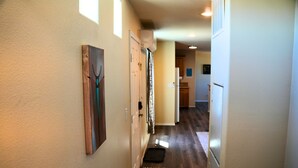 A hallway with a wooden floor, a black and white patterned rug, and a door with a decorative frame. - Quiet Mountain Getaway (Hesperus)