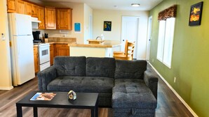 A modern kitchen with wooden cabinets, a dining area with a table and chairs, and a gray sectional sofa in a living room. - Quiet Mountain Getaway (Hesperus)
