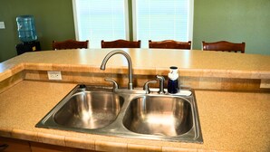 A kitchen with a double stainless steel sink, a water dispenser, and a window with blinds. - Quiet Mountain Getaway (Hesperus)