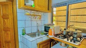 A compact kitchen with a sink, stove, microwave, and wooden cabinets. - 1 Bed Studio Sleeps 2 - Canal View, Parking, Wifi (Douala)