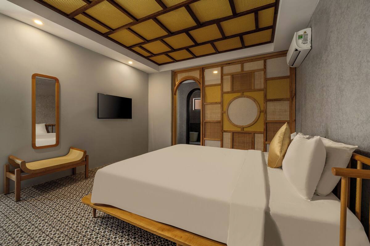 A bedroom with a bed, a bench, a TV, and a traditional-style wall panel.