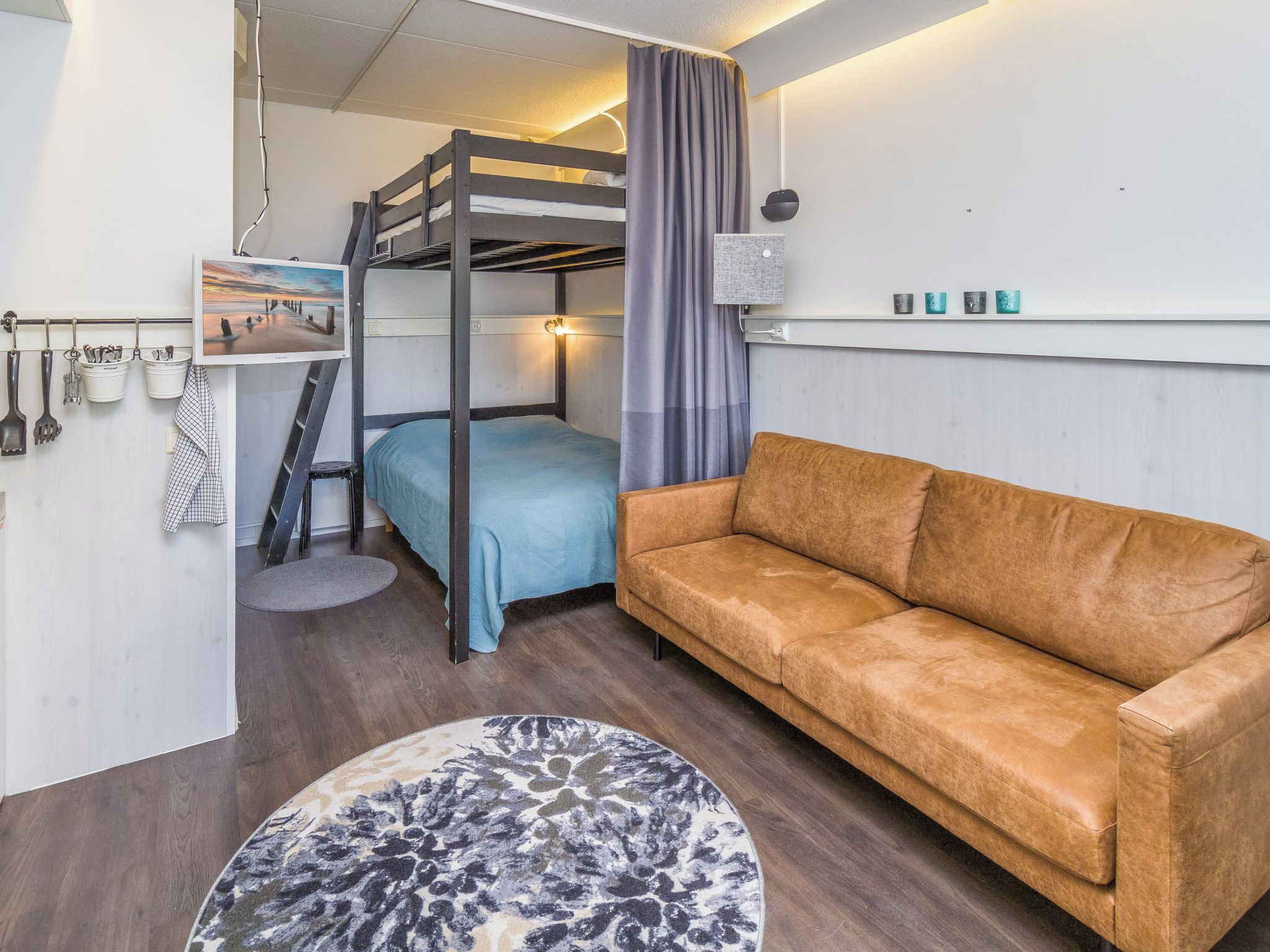 A bunk bed with a headboard, a sofa, a round rug, and a shelf with decorative items.