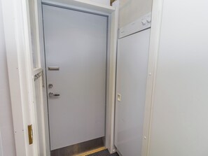 A white door with a metal handle and a keyhole, a small window, and a metal threshold.