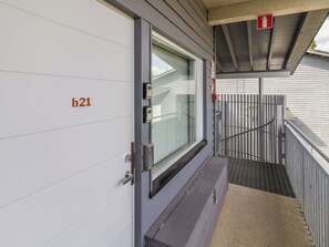 Entrada de hotel con una puerta identificada como 'b21', un ventanal y un letrero de salida de emergencia.
