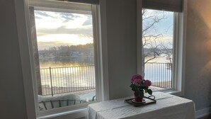 Une pièce avec vue sur un plan d’eau et dotée d’une balustrade. On y trouve une table recouverte d’une nappe blanche et un vase rempli de fleurs.
