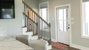 Un intérieur moderne avec un comptoir en marbre, un escalier avec des rampes en bois et un tapis rouge à motifs.