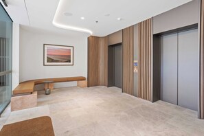 Eine moderne Lobby mit einer gebogenen Bank, einem gerahmten Bild an der Wand und einer Gruppe von Aufzügen.
