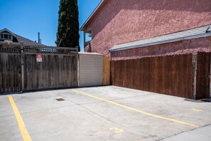 A gated parking area with a garage door and a wooden fence.