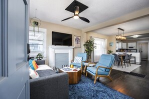 A modern living room with a fireplace, seating area, and a dining table.