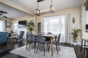 A modern living room with a dining area, a fireplace, and a large window with curtains.