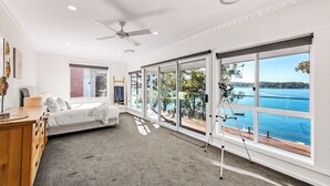 A bedroom with a large sliding glass door leading to a balcony overlooking a body of water. - Catalina Bay - Absolute Lakefront - Jetty - Boat house on waters edge (Fishing Point)