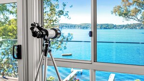 A telescope on a tripod inside a room with large windows overlooking a lake and dock. - Catalina Bay - Absolute Lakefront - Jetty - Boat house on waters edge (Fishing Point)