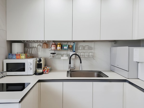 A modern kitchen with white cabinets, a built-in microwave, a sink, and a refrigerator.