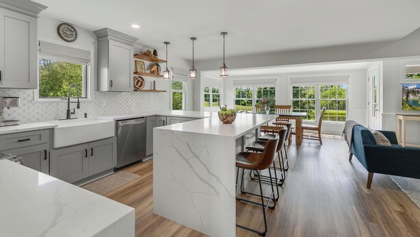 A modern kitchen with a central island, bar stools, and a dining area with a view of the outdoors. - Historic Farmhouse with Pool & Hot Tub in Wine Country, Near Washington, DC (Hamilton)