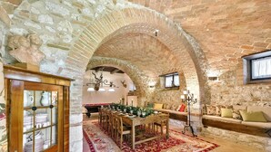 A rustic dining area with a brick archway, wooden furniture, and a red patterned rug. - Luxurious independent villa with 12 beds in Val d'Orcia (Sarteano)