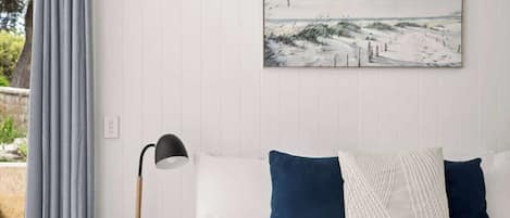 Um quarto com uma cama, uma mesa de cabeceira, uma luminária e um quadro na parede.
