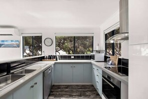 Una cuina moderna amb forn integrat, un rentapeus i una finestra amb vista a un jardí.