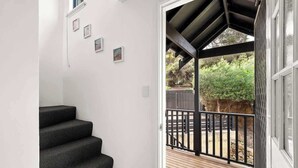 A staircase leading to a covered outdoor area with a wooden deck and a black railing. - Surfers Paradise—Oceanview Garden Beach House (Yallingup)