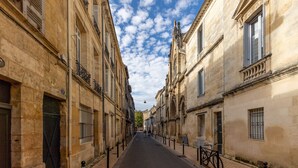 Une rue étroite bordée d’immeubles anciens en pierre, dotés de fenêtres grillagées, et sur le trottoir, un vélo est garé.