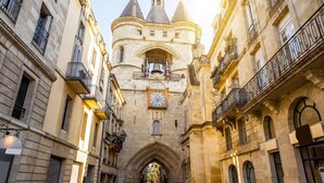 Une rue étroite bordée de bâtiments historiques, un imposant beffroi et l’entrée d’une cathédrale.