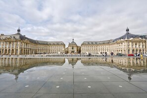 Un grande edificio storico con un cortile centrale e una superficie d'acqua riflettente.