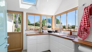 Cocina moderna con ventanas amplias, armarios blancos y un tragaluz.
